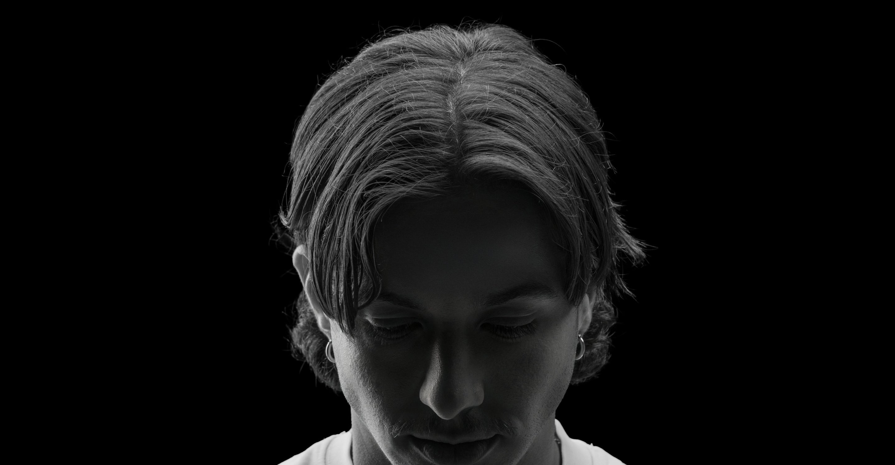 Black and white portrait of a person with a neutral expression on a black background