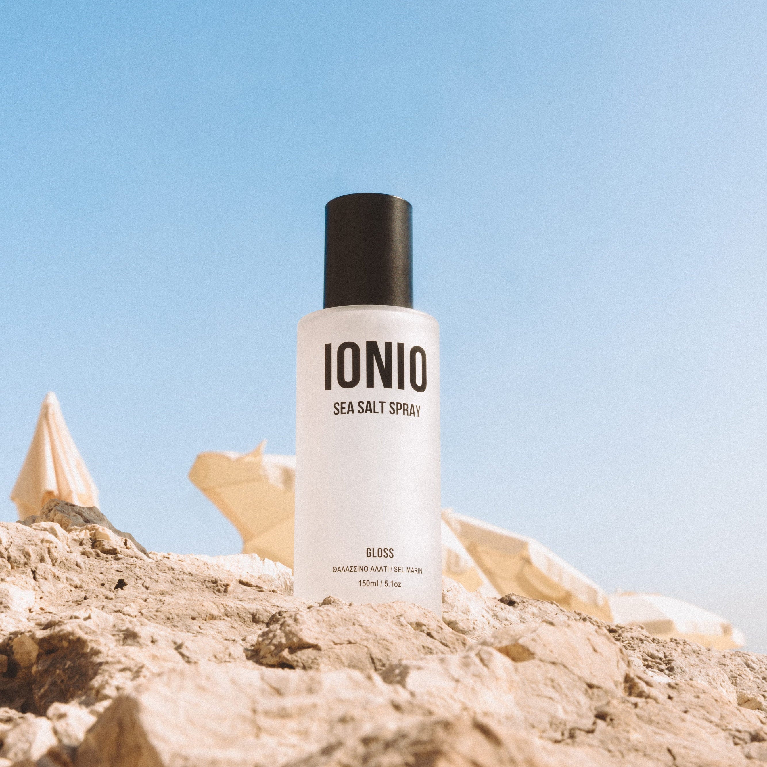 IONIO sea salt spray bottle on a rocky surface with a clear blue sky.