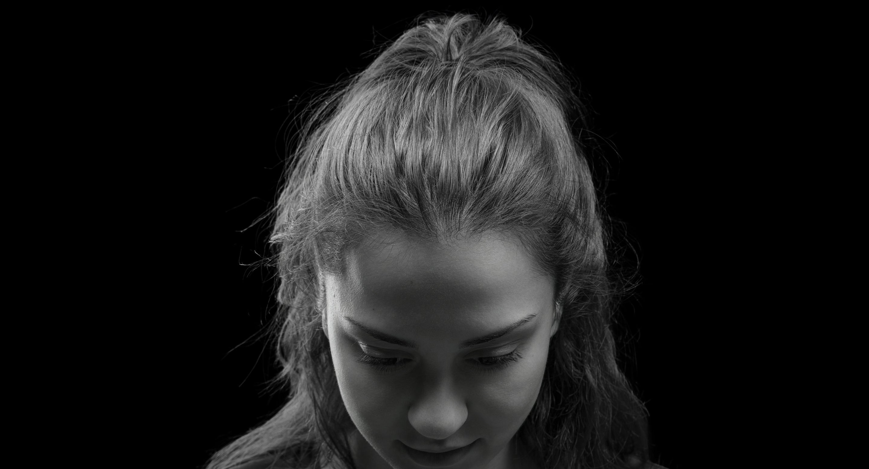 Black and white portrait of a woman with a neutral expression on a black background